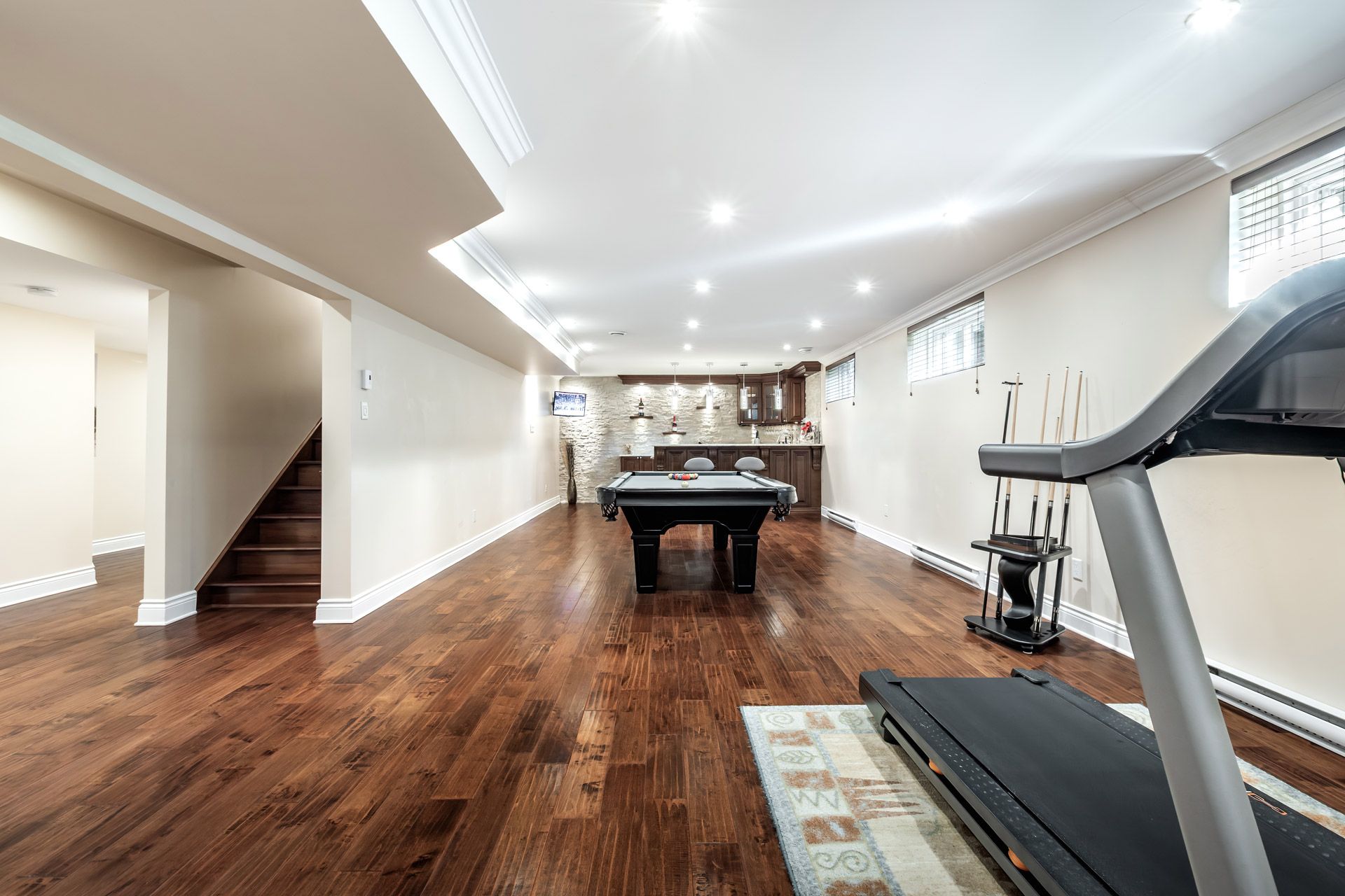 Spacious finished basement with hardwood floors, pool table, treadmill, and recessed lighting