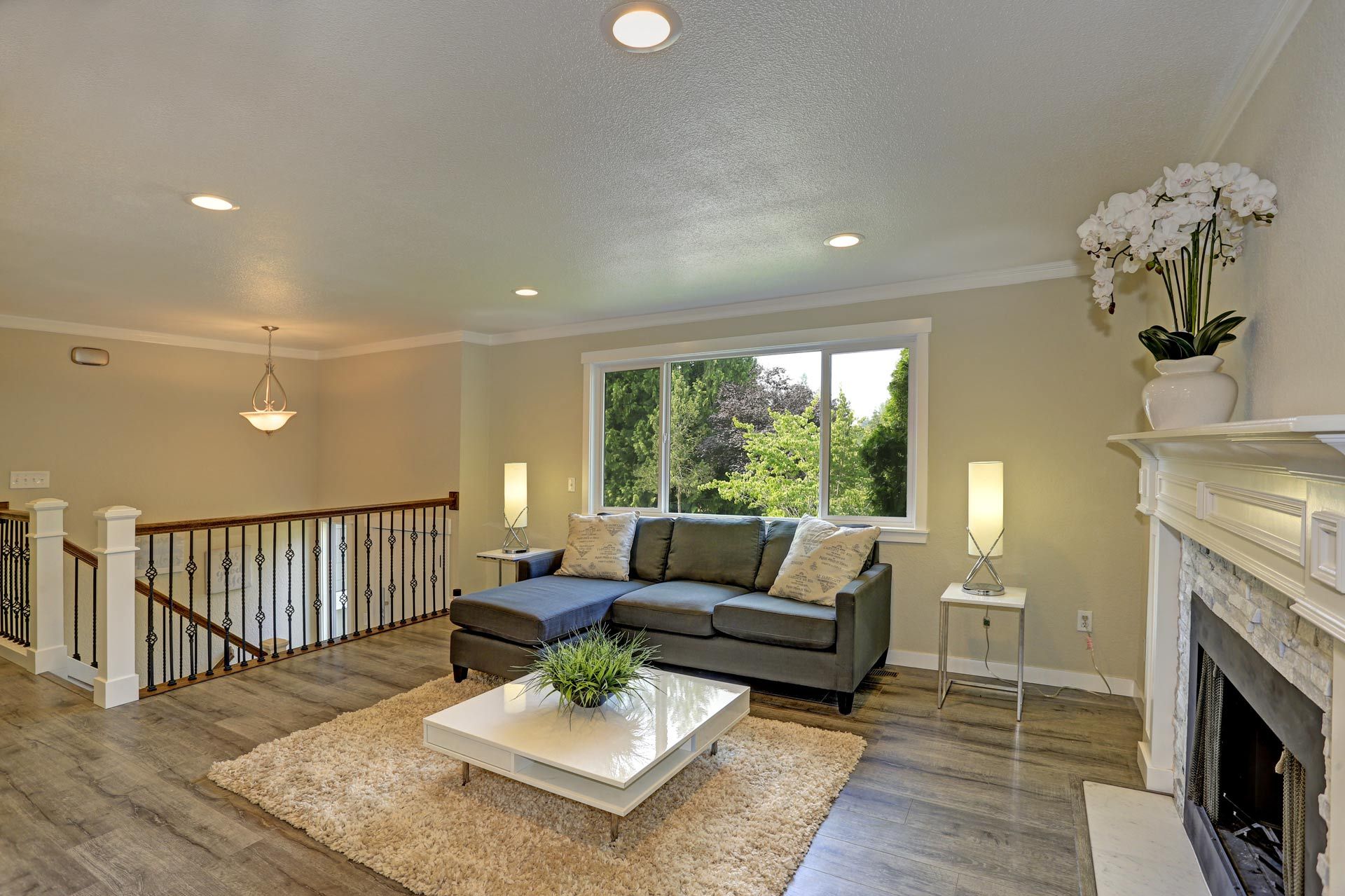 Bright living room with gray sectional, white coffee table, fireplace, and sliding glass doors