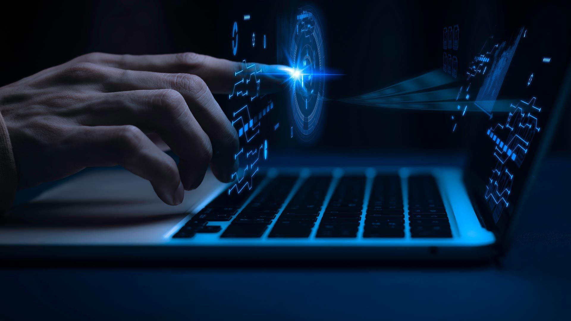 Hands typing on a laptop with glowing blue digital interface and cybersecurity graphics