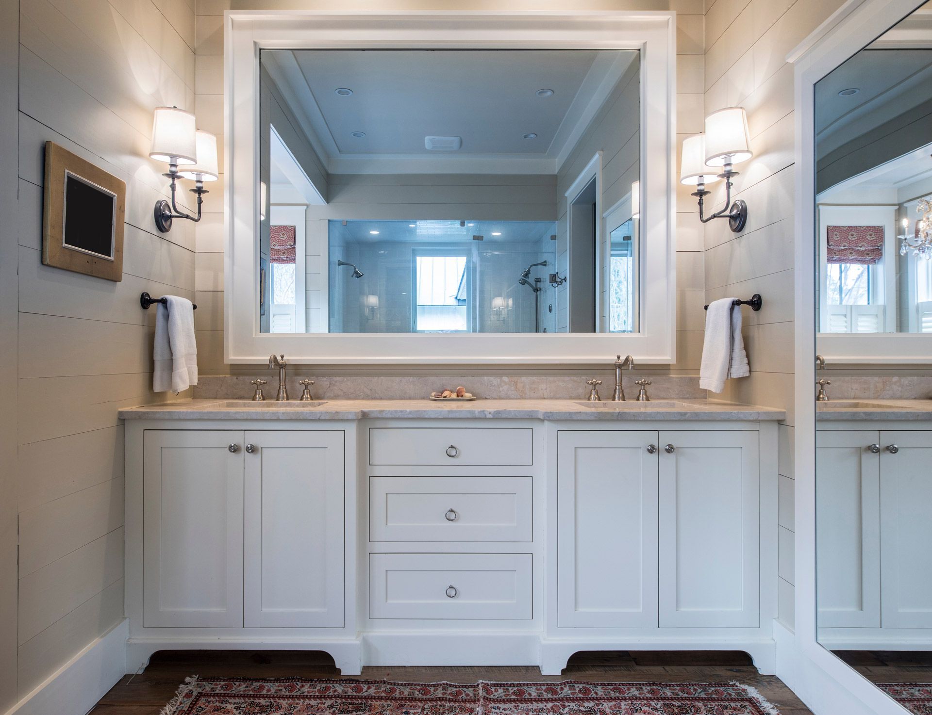 Elegant white bathroom vanity with double sconces and large mirror above a marble countertop