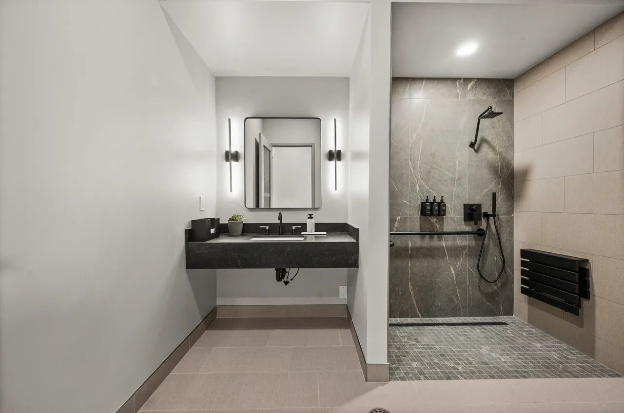 Modern bathroom with floating sink, mirror, and glass shower with black fixtures