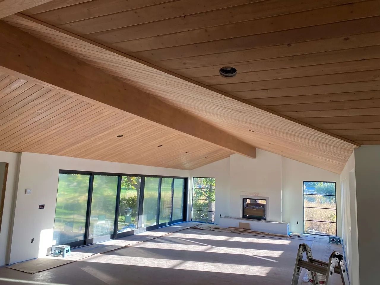 Spacious modern room with wood-paneled vaulted ceiling and large sliding glass doors opening to a patio.