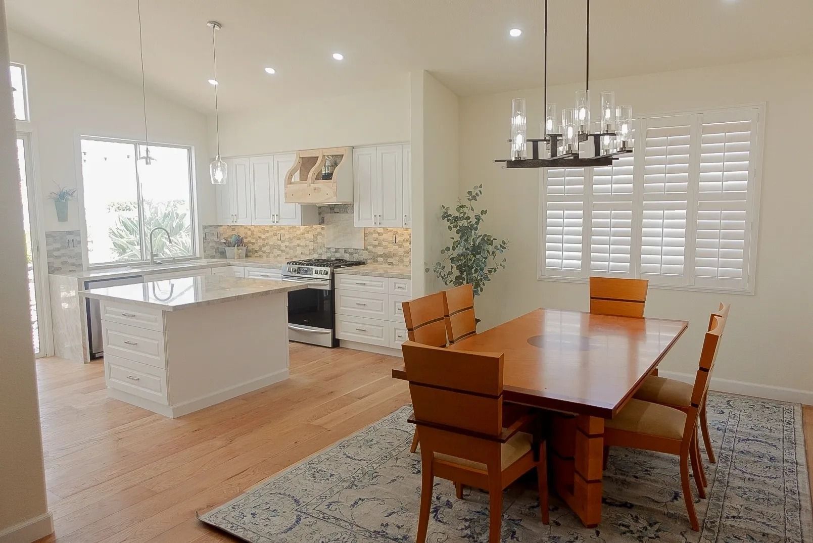 Bright open kitchen and dining area with white cabinets, wood table, and island.