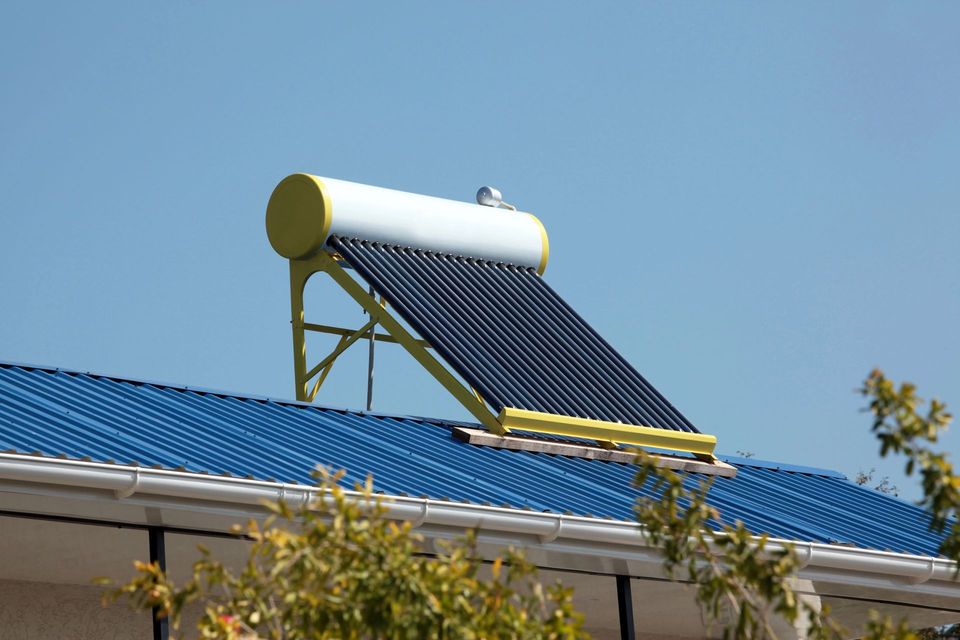 Scaldabagno solare su un edificio con il tetto blu sotto un cielo limpido