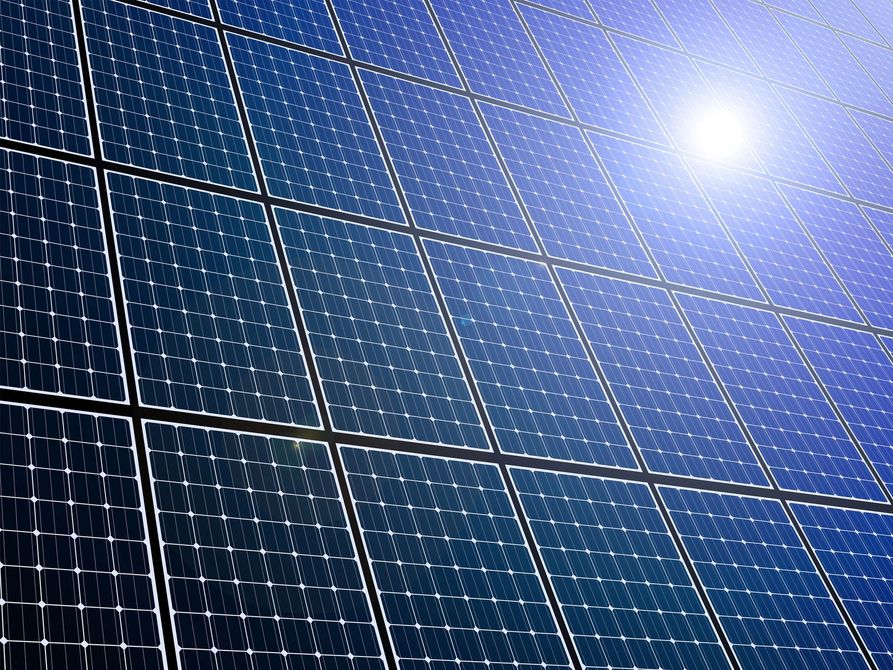 Pannelli solari che riflettono la luce intensa del sole contro un cielo azzurro e limpido.