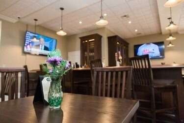 A restaurant interior with a dark wooden bar and tables, several TVs, and hanging lights.