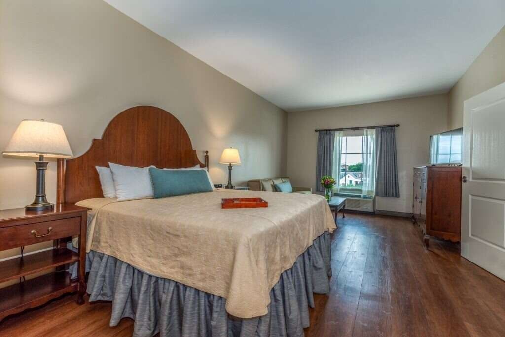 Bedroom with king bed, nightstand, couch, and a window with a view; hardwood floors.