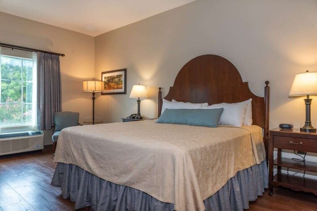 Bedroom with a queen-sized bed, wooden furniture, blue accents, and a window with natural light.