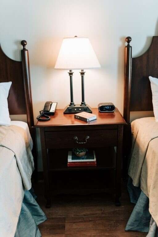 Two twin beds with a nightstand, lamp, phone, and clock.