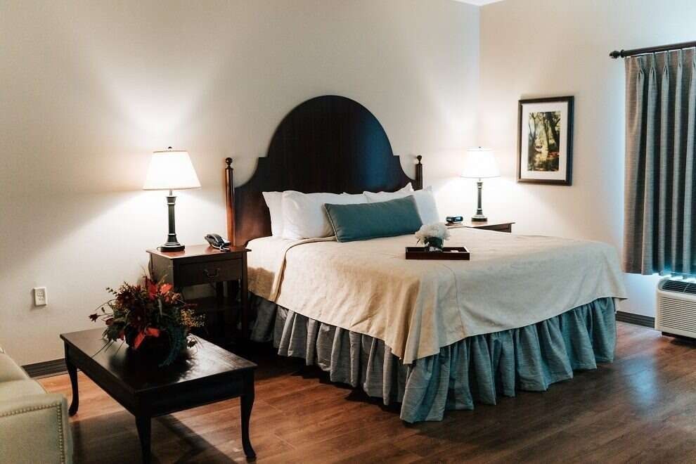 Bedroom with a bed, nightstands, lamps, artwork, and a small table with flowers.
