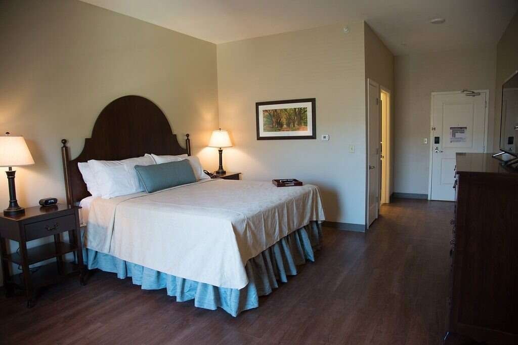Hotel room with a bed, bedside tables with lamps, and a doorway.