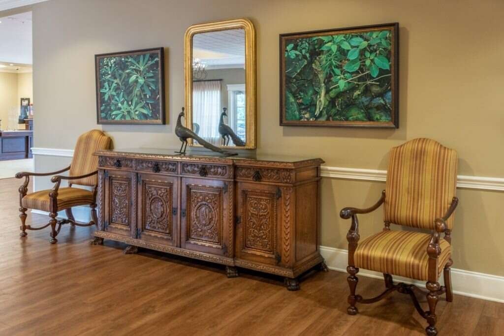Wooden console with art and chairs in an entryway.