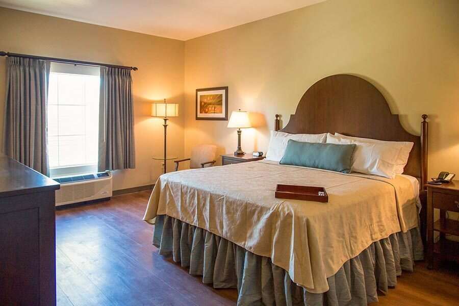 Bedroom with a bed, dresser, window, and lamps; warm color scheme.