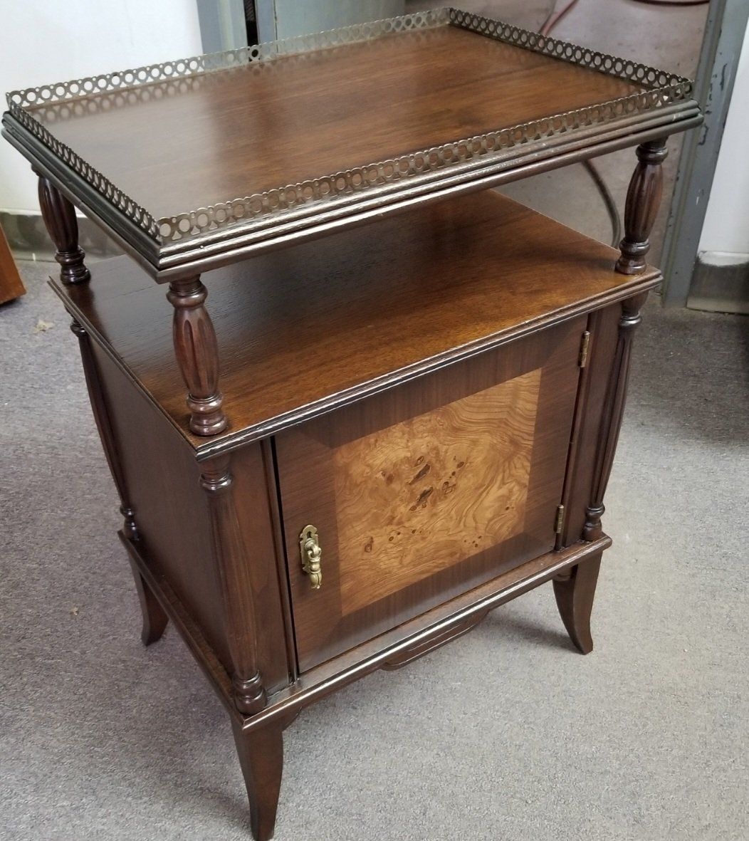 A wooden side table with a gallery rail top, an open shelf, and a cabinet door with decorative burl wood inlay.