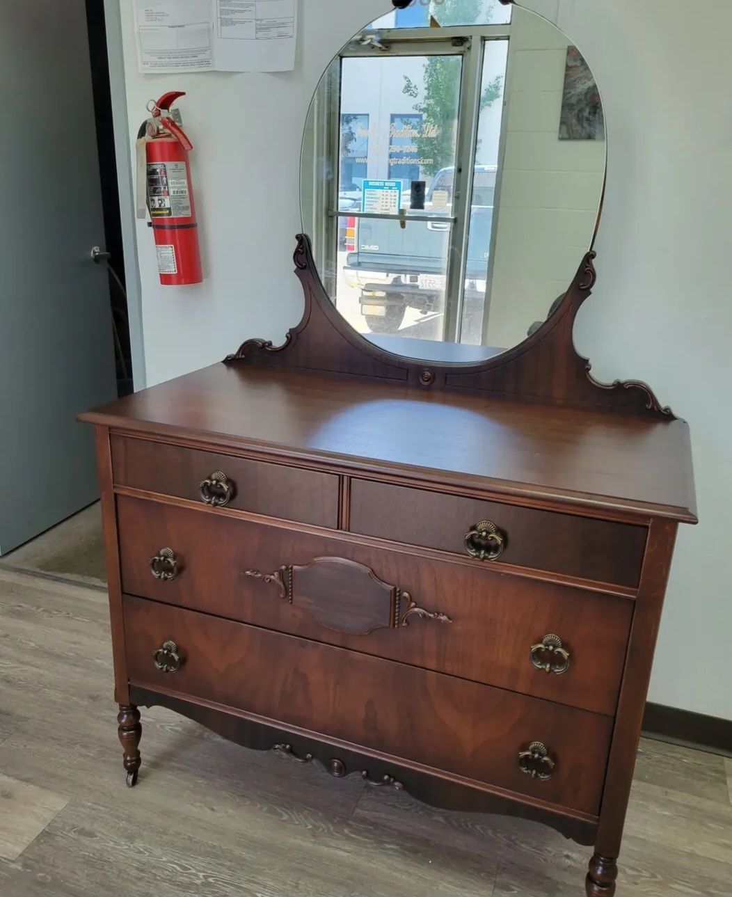 A wooden side table with a gallery rail top, an open shelf, and a cabinet door with decorative burl wood inlay.