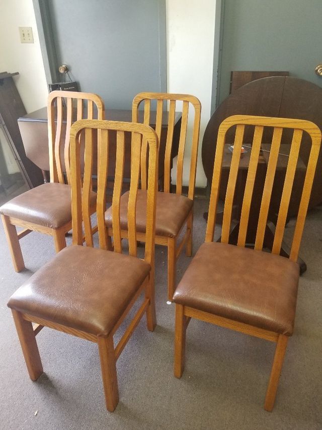 Four wooden dining chairs with brown seats arranged in a room