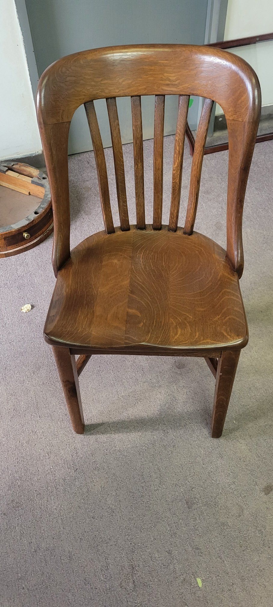 Wooden dining chair with a curved back and brown seat on a carpeted floor