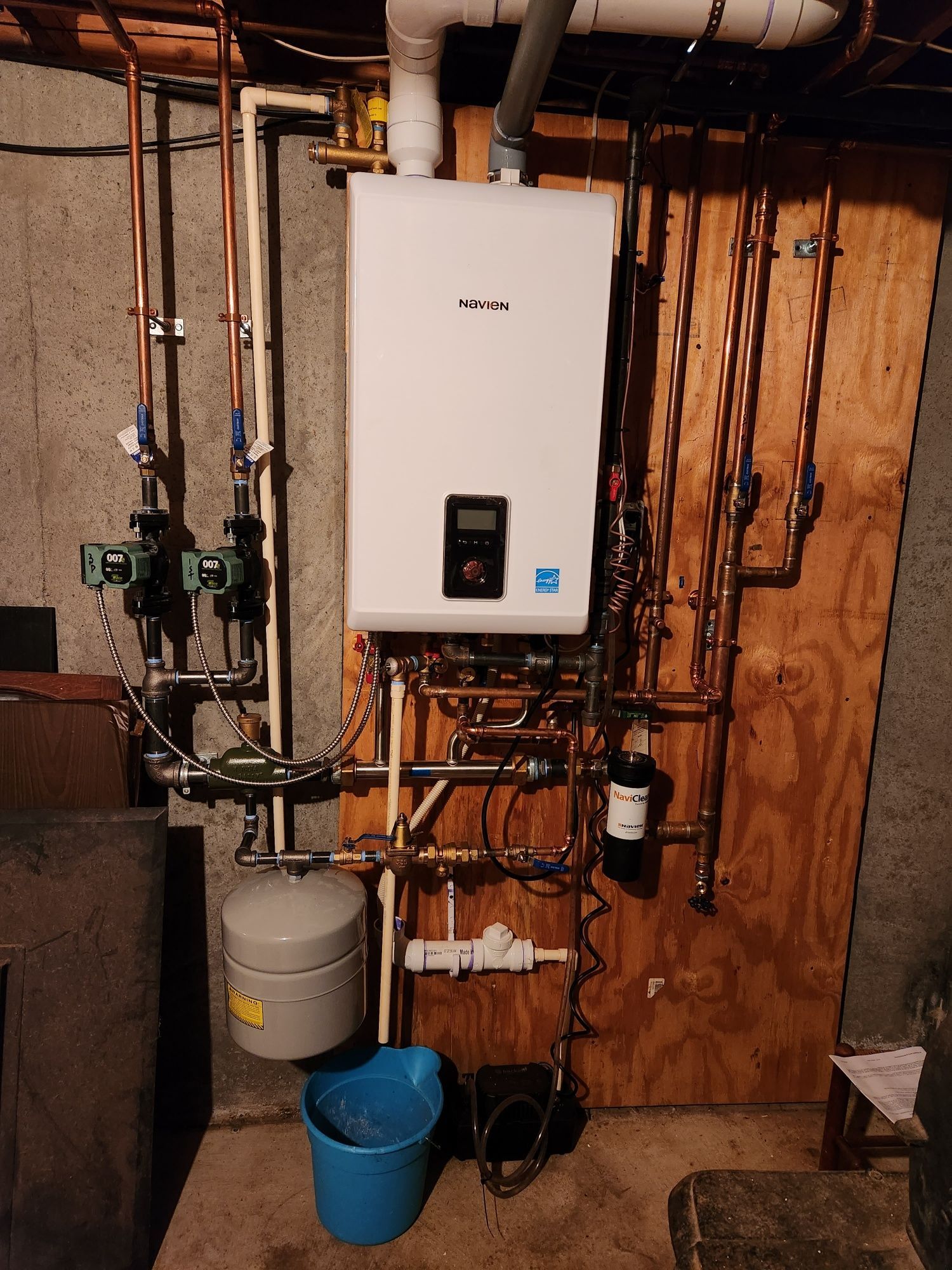 A newly installed Navien natural gas boiler system with copper piping, replacing an old oil heating setup