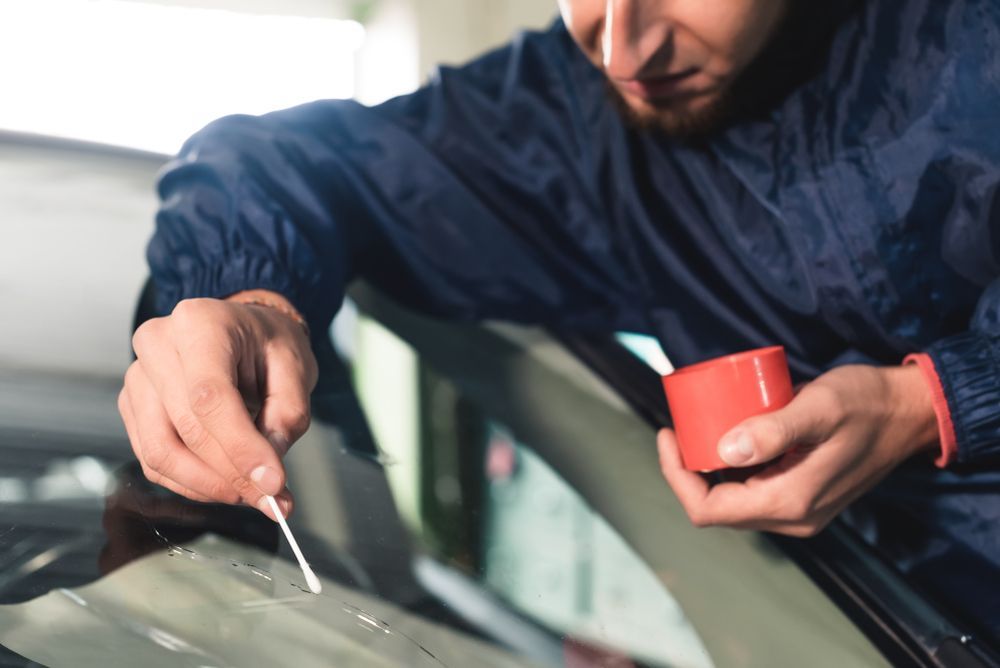 A Man is Fixing a Broken Windshield on a Car — Crakka Windscreens in Diamond Beach, NSW