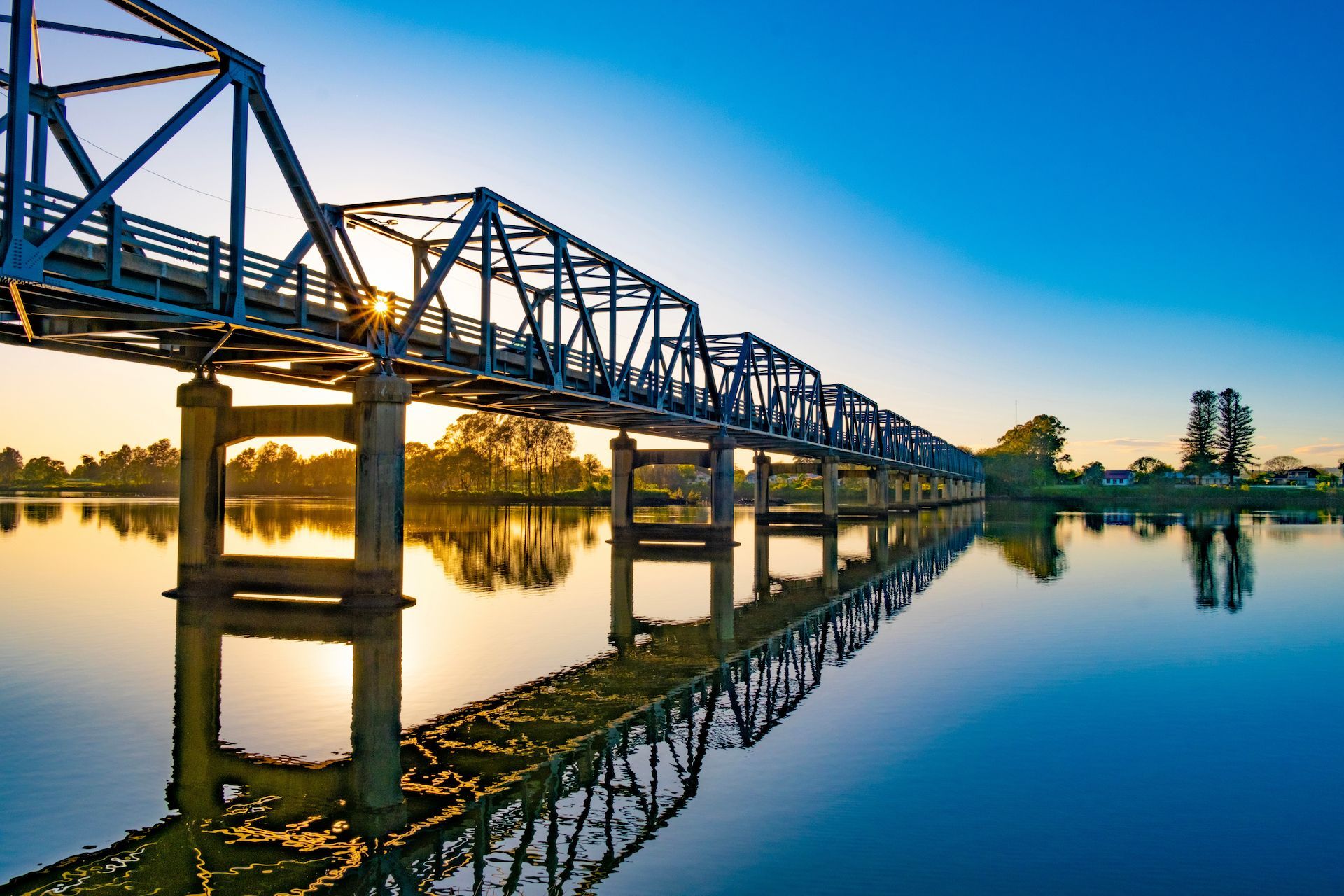 A Bridge Over a Body of Water With the Sun Reflected in the Water — Crakka Windscreens in Taree, NSW