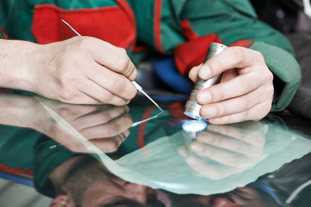 A Man is Working on a Windshield With a Tool — Crakka Windscreens in Harrington, NSW
