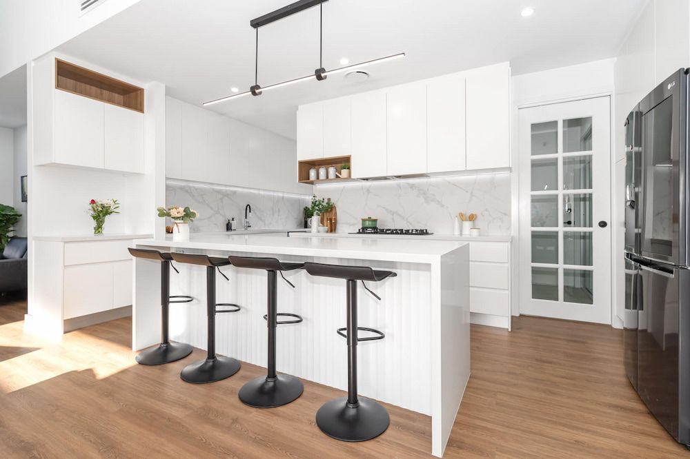 A Kitchen With White Cabinets And Black Stools And A Large Island — ASM Joinery In Fyshwick, ACT