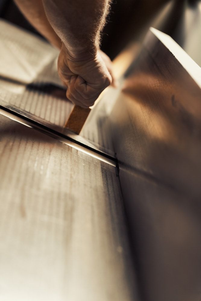 A Person Is Cutting A Piece Of Metal With A Saw — ASM Joinery In Fyshwick, ACT