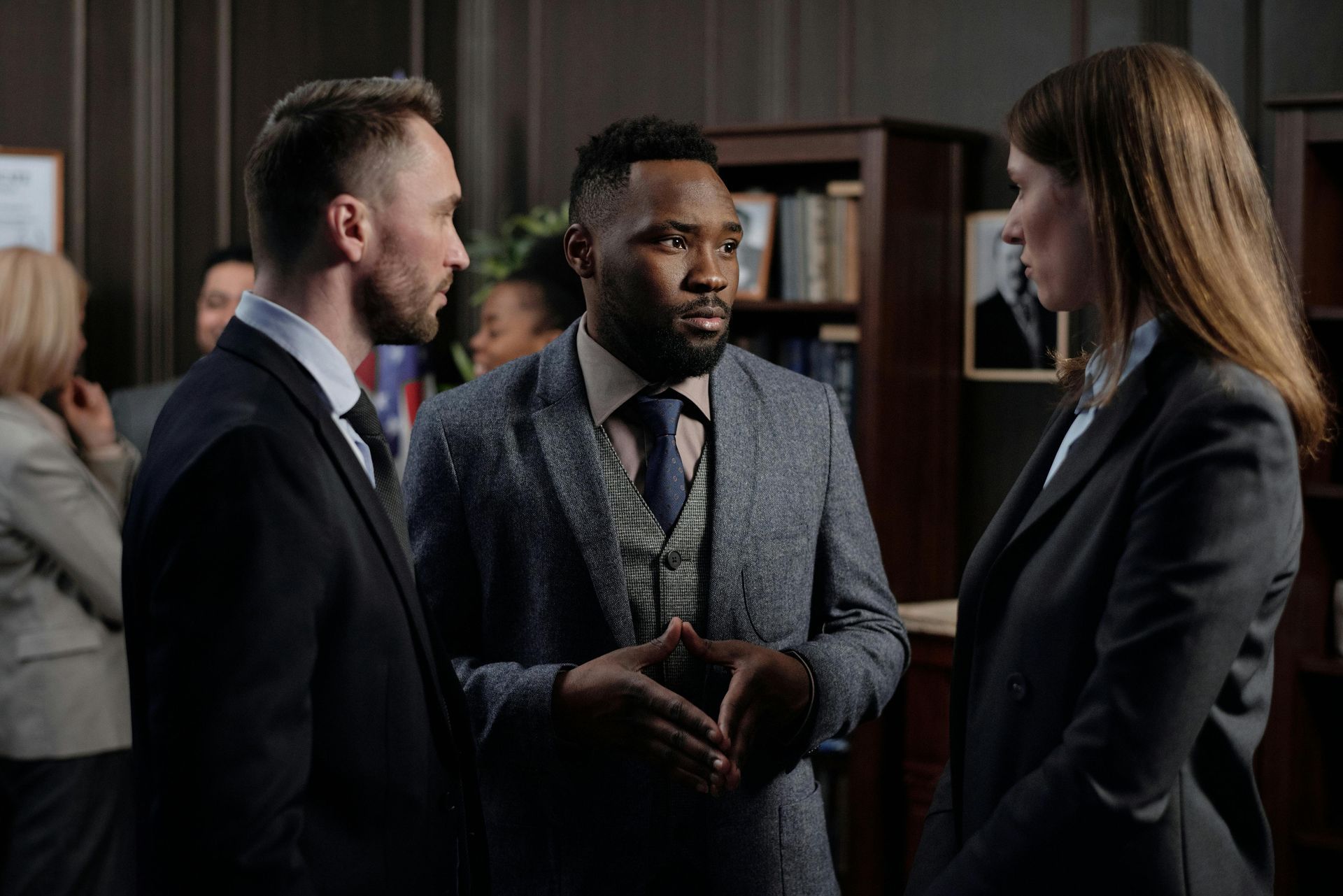 Three professionals in suits discussing in an office setting