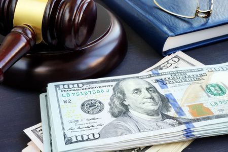 Gavel, $100 bill, and law book, symbolizing legal fines or financial judgment