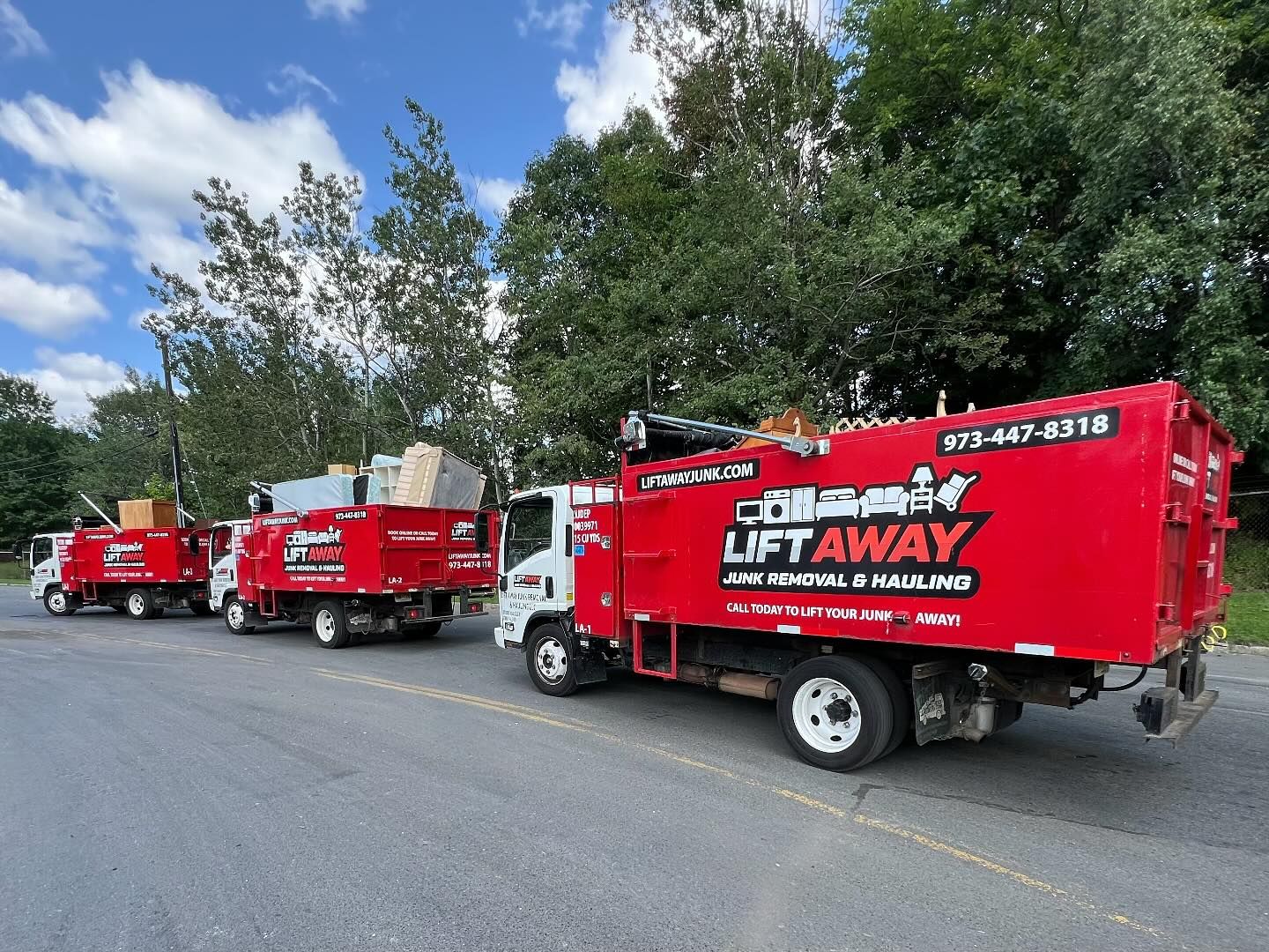 Three red Lift Away trucks parked, loaded with junk, ready for removal.