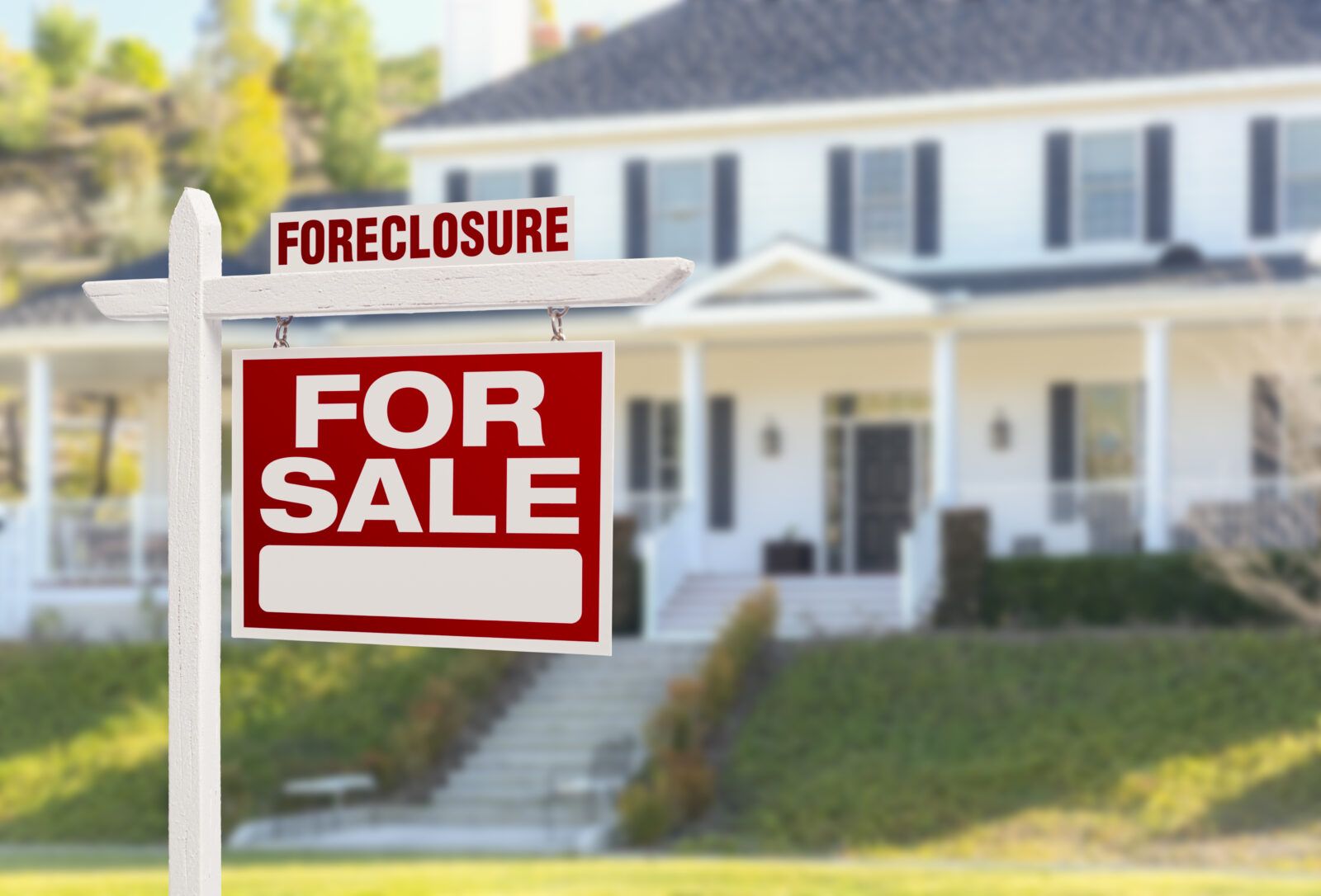 Foreclosure home for sale sign in front of a two-story house with a white exterior and black shutters.