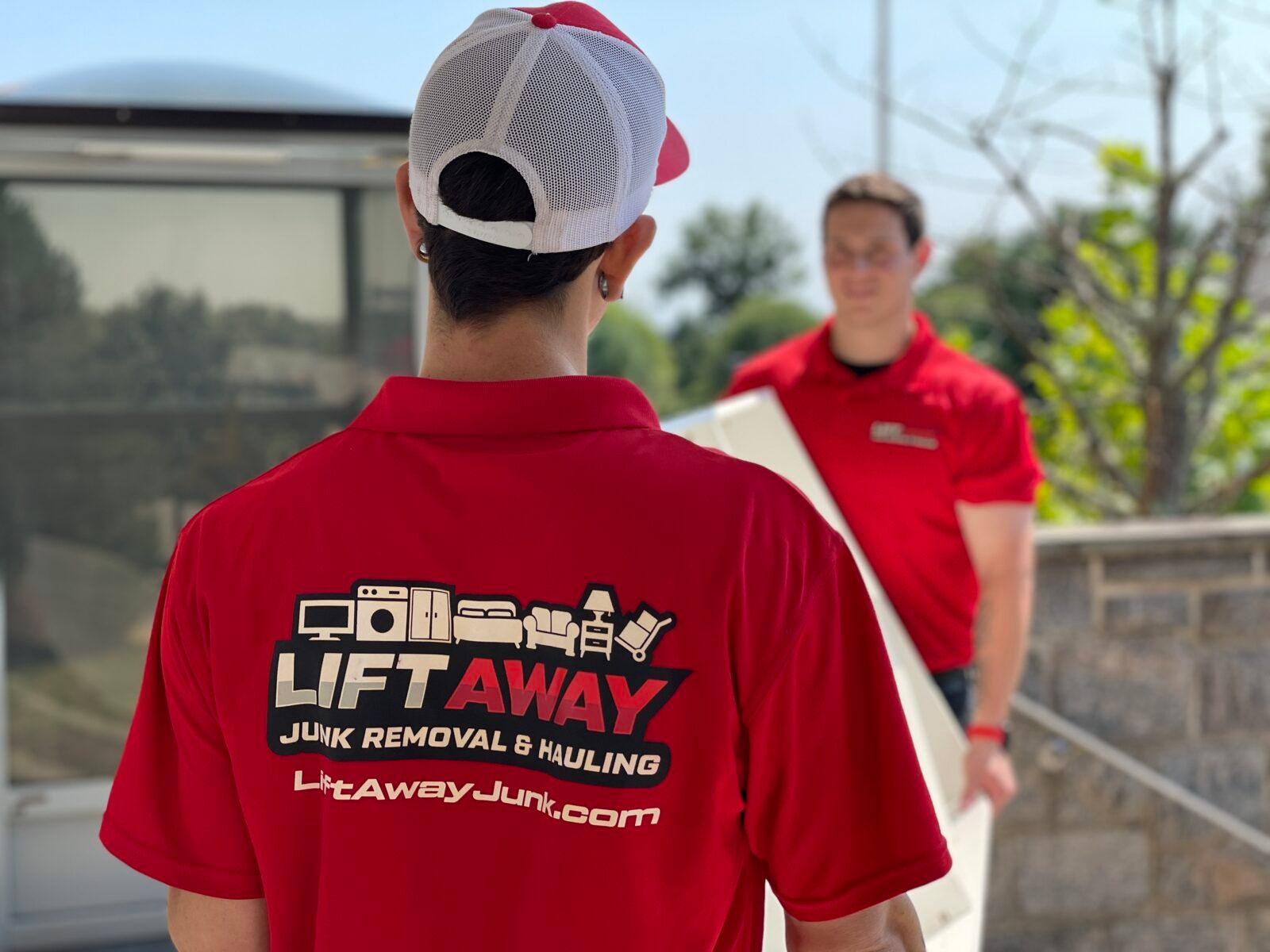 Two men in red shirts, one carrying a white object, likely junk removal. The company logo is visible.