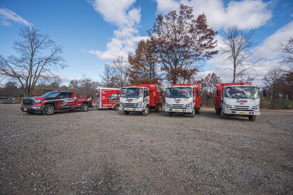 A line of service vehicles on a gravel lot under a blue sky.