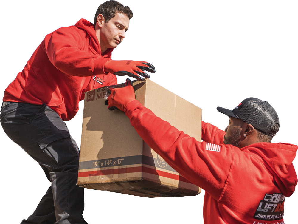 Two movers in red hoodies lift a cardboard box together.