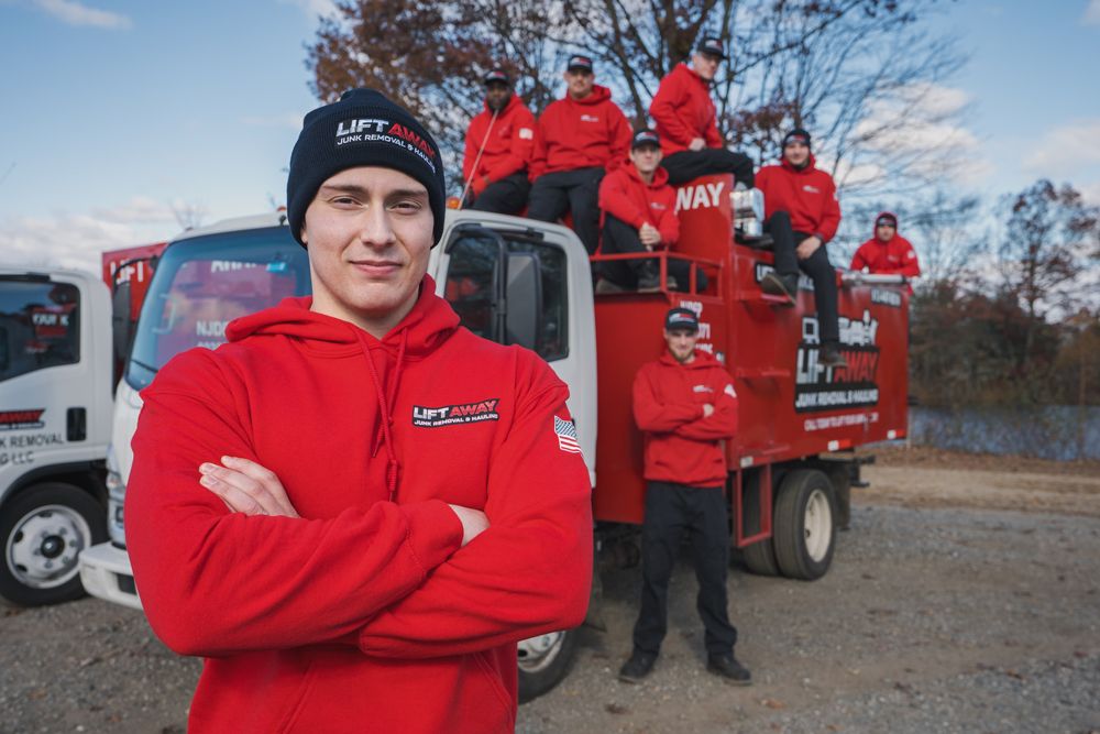 A man in a red hoodie stands in front of a truck with a team wearing red.