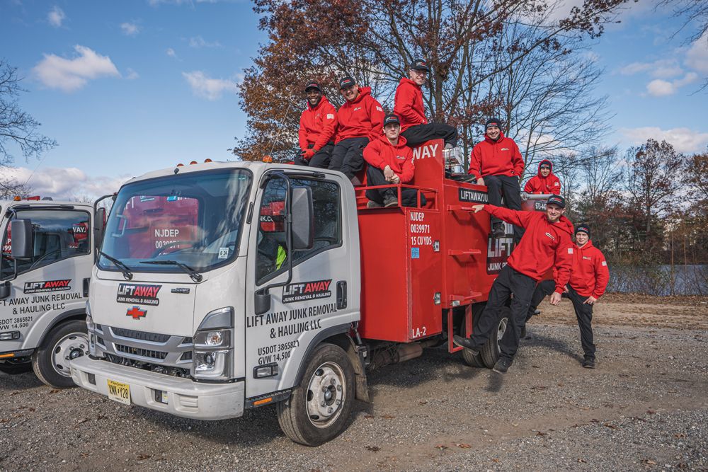 Men in red jackets pose on a white and red truck in a fall setting.