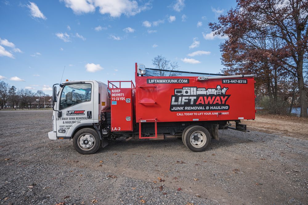 Red and white Collins Lift Away truck on gravel, parked outdoors on a sunny day.