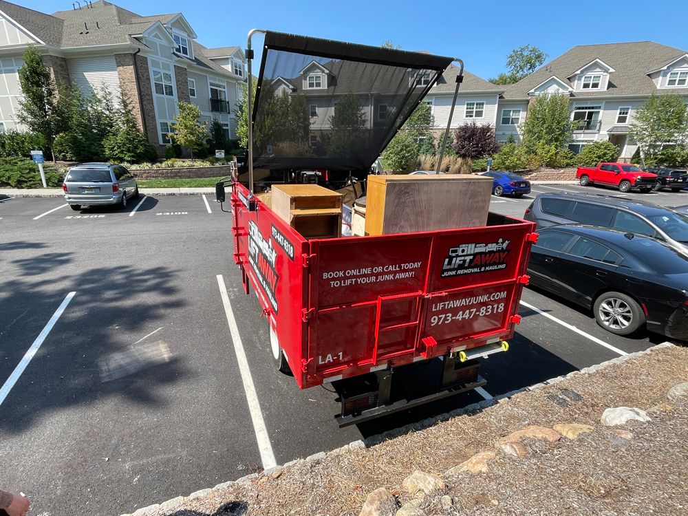 Red dumpster truck in a parking lot, loaded with items.
