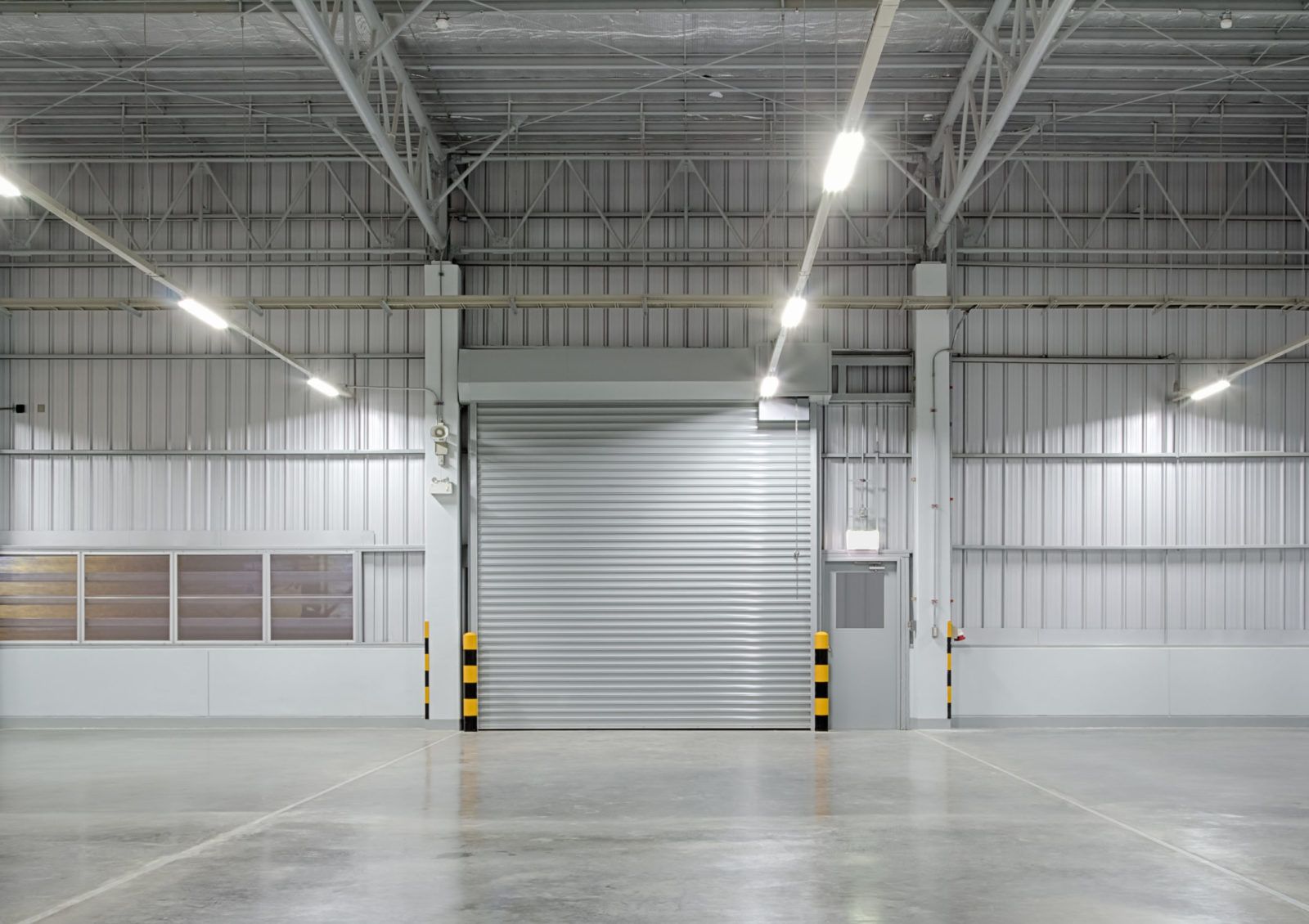 Empty industrial warehouse with a closed metal door.