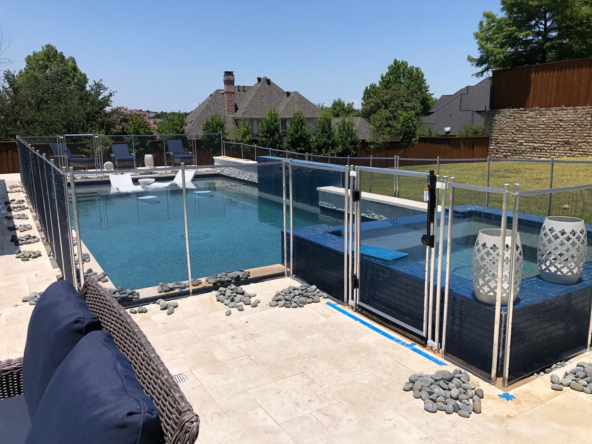 Backyard swimming pool with a safety fence and netted cover, surrounded by lounge chairs and patio furniture