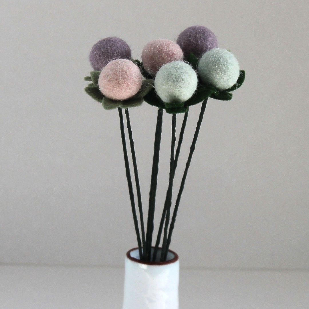 Boeket vilten bloemen in pastelkleuren, gepresenteerd in een witte vaas.