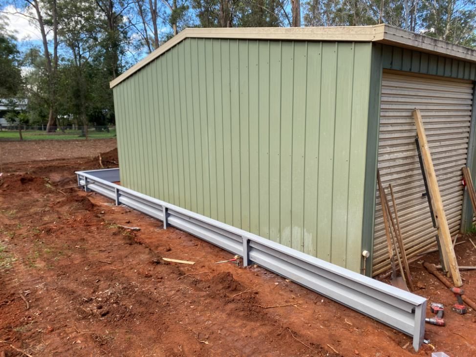 A Green Shed is Sitting in the Middle of a Dirt Field — Ape Earthmoving In Westbrook, QLD