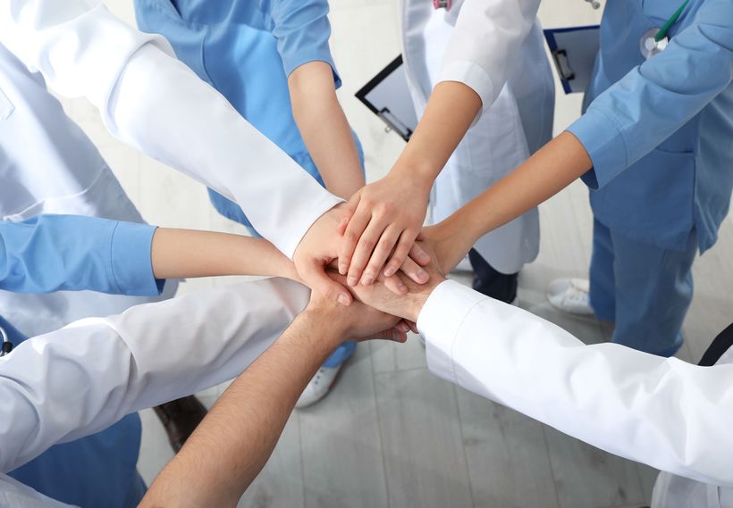 Team of healthcare workers stacking hands in a hospital huddle Team of healthcare workers stacking hands in a hospital huddle