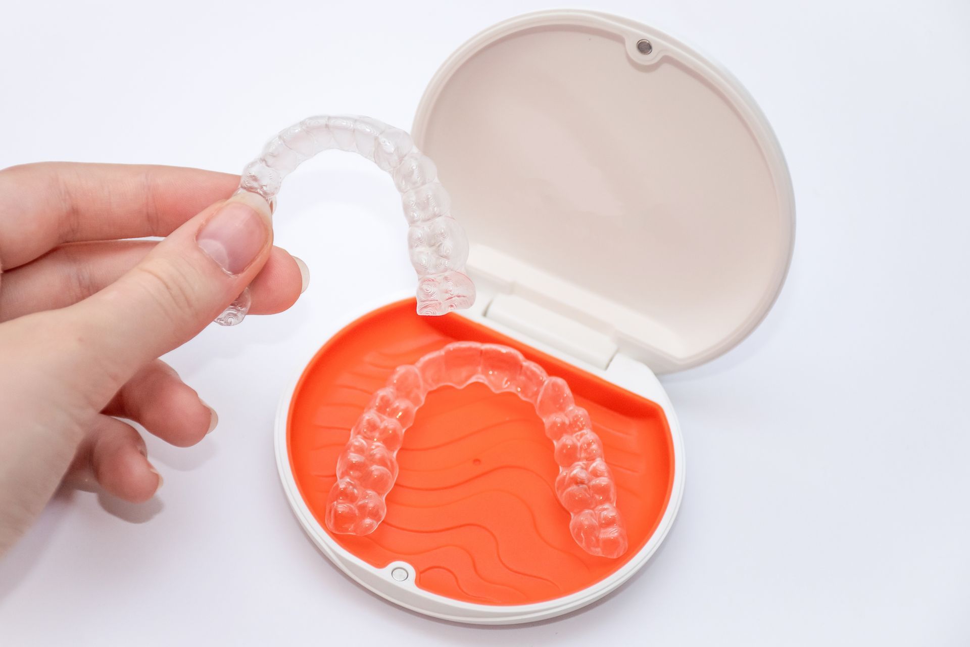 Hand holding an open black case with a clear blue dental mouthguard inside