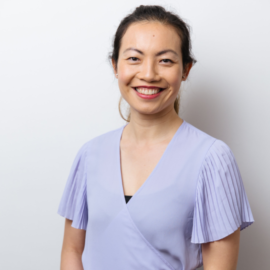 Smiling woman in a light lavender top against a plain gray background Smiling woman in a light lavender top against a plain gray background