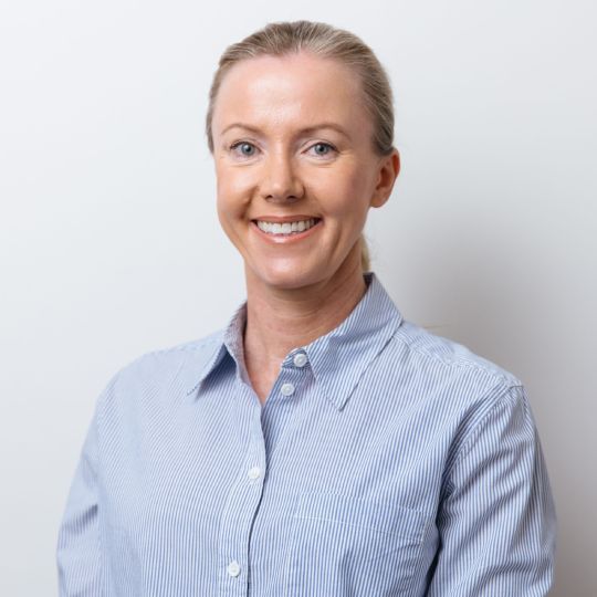 Smiling person in a light blue striped button-up shirt against a white background Smiling person in a light blue striped button-up shirt against a white background