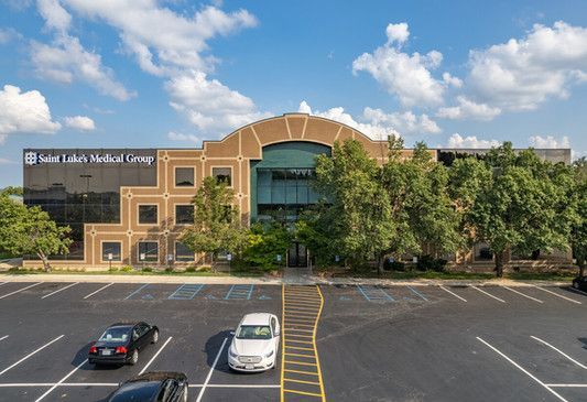 A parking lot in front of a large building with cars parked in front of it.