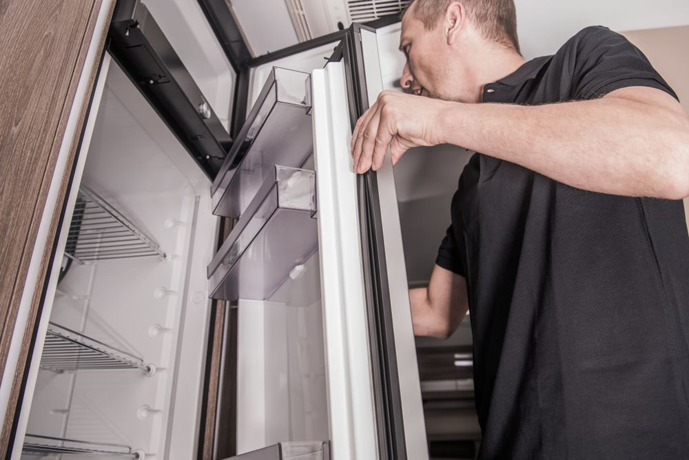 A Man Is Opening The Door Of A Refrigerator — NQ Fridge & Freezer Seals In Manoora, QLD