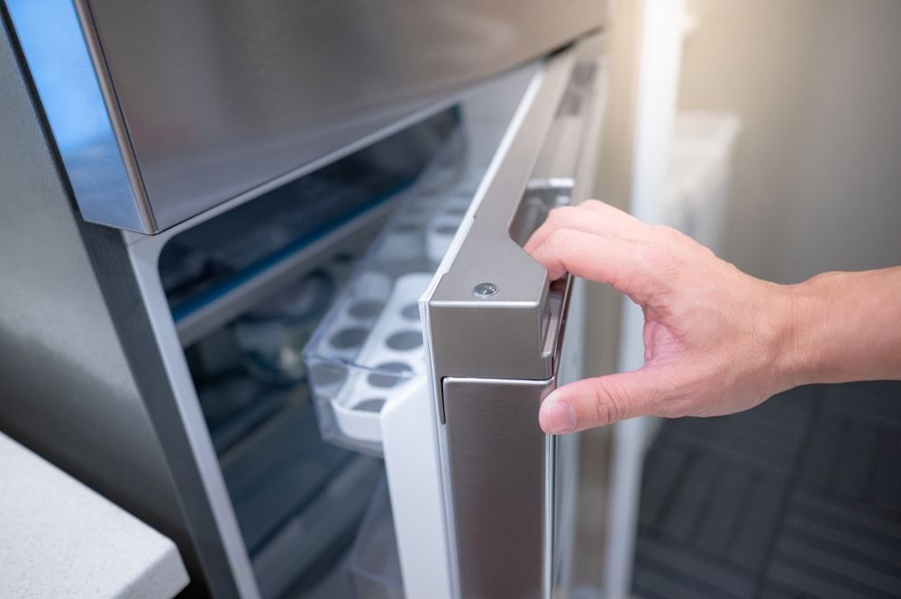 A Person Is Opening The Door Of A Refrigerator — NQ Fridge & Freezer Seals In Manoora, QLD