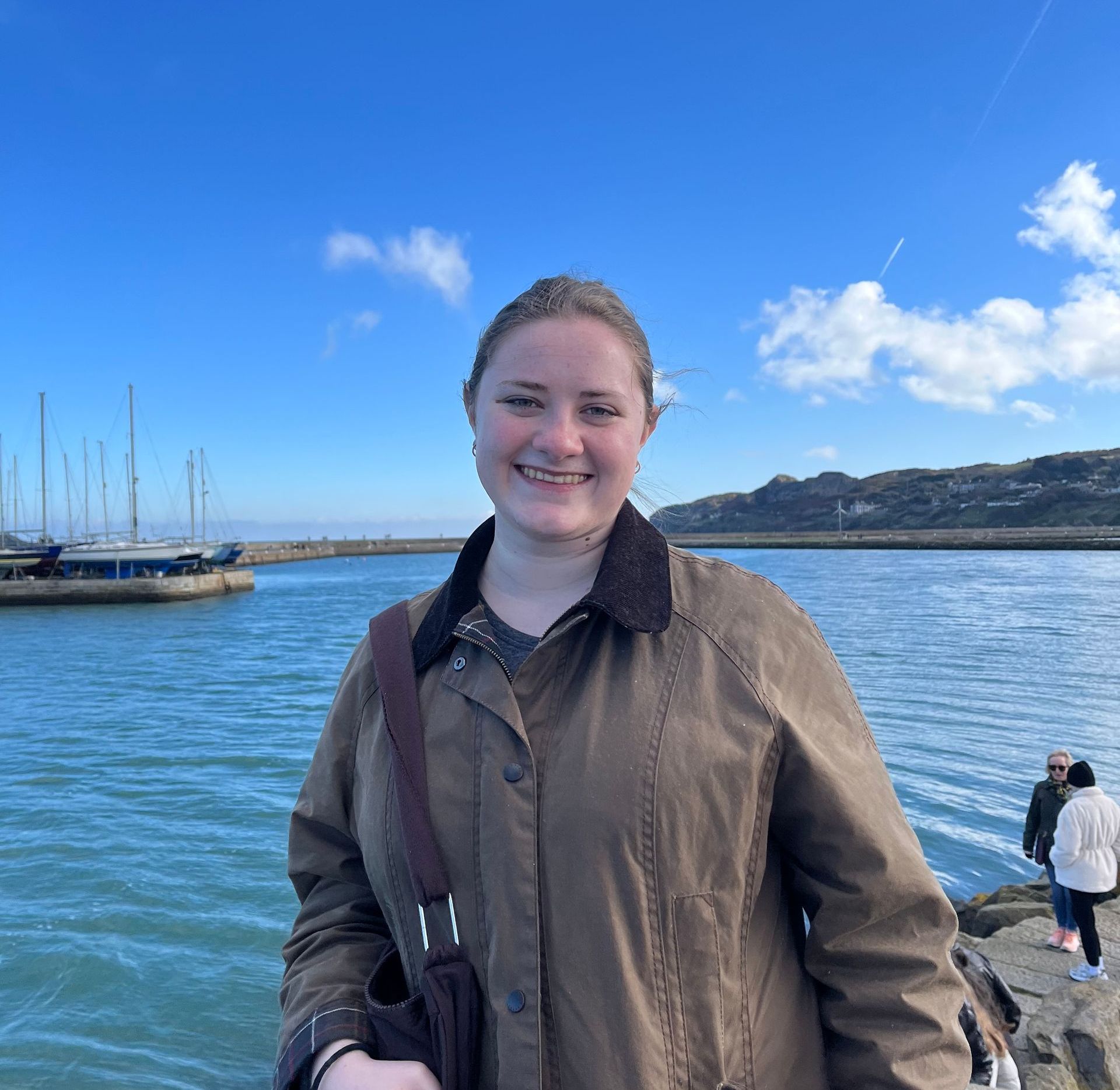 Hannah Suggs in the foreground, water, blue sky, and small boats behind her. Travel Abroad, Ireland and France